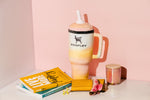 Large pastel plush tumbler-shaped Woofley dog toy styled with books and a candle on a pink backdrop